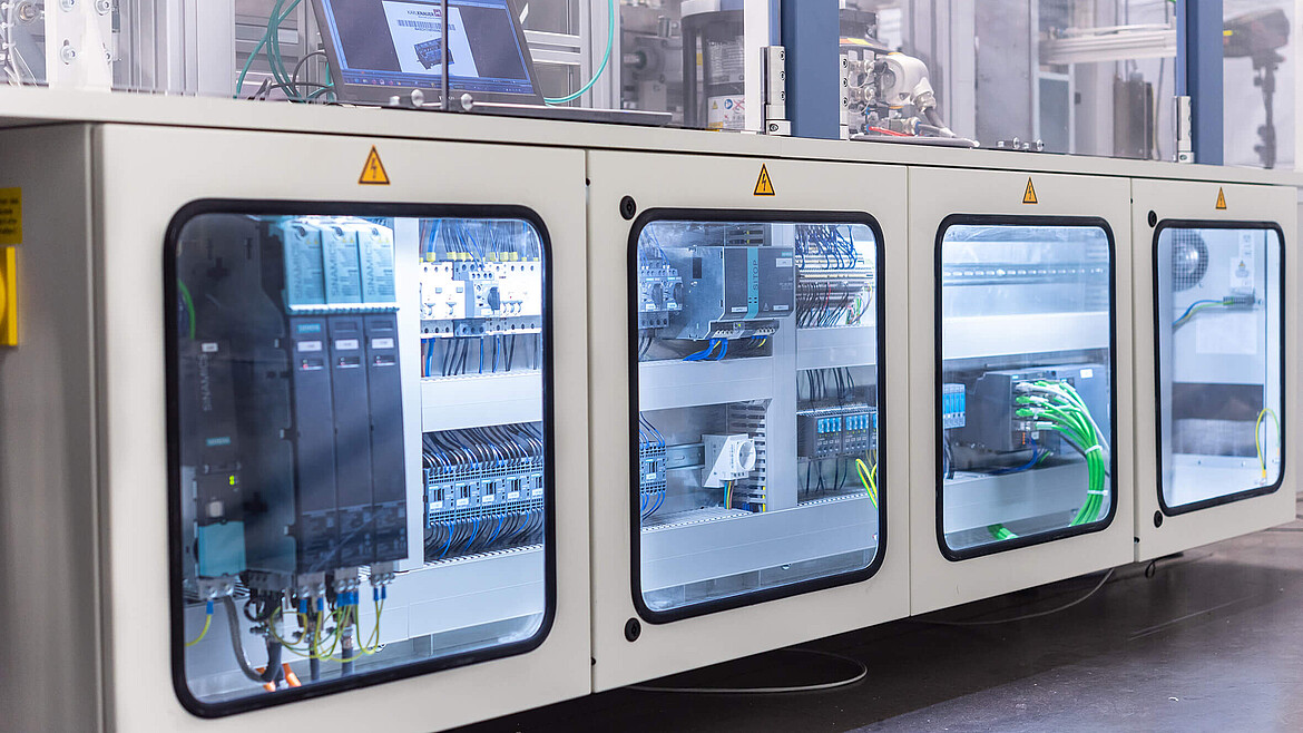 Kabelanschlüsse einer Verpackungsmaschine hinter Glasfenstern